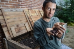 Chris Cano, of Gainesville Compost, poses with worms near some of his compost bins.